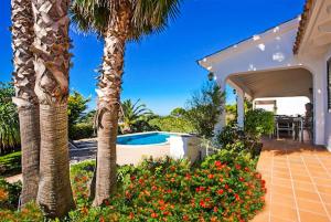 a house with a swimming pool and palm trees at Bini Cel in Binibeca