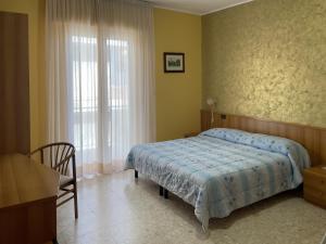 a bedroom with a bed and a chair and a window at La Lanterna in Silvi Marina