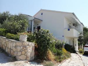 a white house with a stone wall at Apartman Zlata in Ražanac