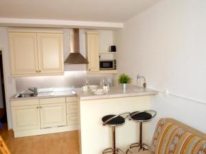 a kitchen with white cabinets and stools in it at Studio Leif by Interhome in Zell am See