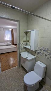 a bathroom with a toilet and a sink and a bed at Park Avenue Kobuleti in K'obulet'i