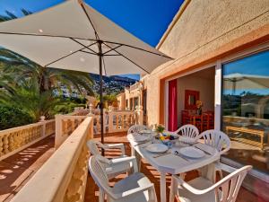 un tavolo con sedie bianche e un ombrellone su un patio di Apartment Canuta Baja-8 by Interhome a La Canuta