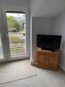 a living room with a flat screen tv on a stand next to a door at Nythfa Guest House in Saundersfoot