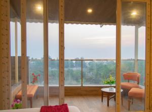 Habitación con ventanas grandes, mesa y sillas. en Octave Rococco Morjim, en Goa Velha