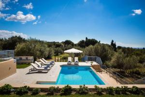 a swimming pool with lounge chairs and an umbrella at Forget me not Villa No 2 in Svoronata