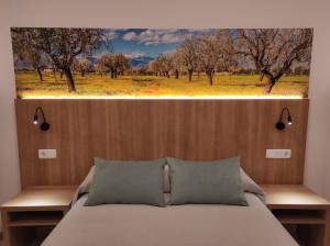 een slaapkamer met een bed met een schilderij aan de muur bij Hostal Nadal in Sóller