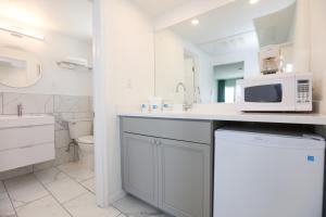 ein weißes Badezimmer mit einem Waschbecken und einer Mikrowelle in der Unterkunft The Heritage Inn in Cape May