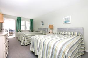 2 Betten in einem Schlafzimmer mit grünen Vorhängen in der Unterkunft The Heritage Inn in Cape May