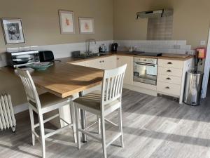 a kitchen with a wooden table and chairs at Pool House, farm stay in Brackley