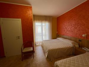 a bedroom with two beds and a chair and a window at La Lanterna in Silvi Marina