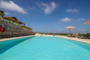 a large blue swimming pool with an umbrella at The Olive Hill Guesthouse in Batalha