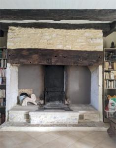 a stone fireplace in a room with a book shelf at LE PARDÈS BnB in Rocamadour