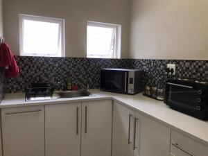 a kitchen with a sink and a microwave at A Touch of Red in Oudtshoorn