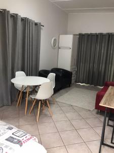 a living room with a table and chairs and a refrigerator at A Touch of Red in Oudtshoorn +7 photos