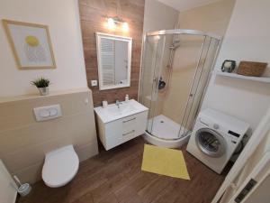 a bathroom with a shower toilet and a washing machine at Adam apartmán in Košice