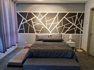 マラッカにあるLuxury Bali Homestayのベッドルーム(幾何学的ヘッドボード付きの大型ベッド1台付)