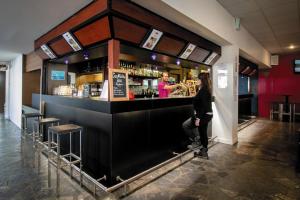 a woman standing at a bar in a restaurant at Belambra Clubs Gourette - Lou Sarri in Gourette