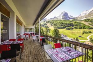un restaurant avec des tables et des chaises sur un balcon avec des montagnes dans l'établissement Belambra Clubs Gourette - Lou Sarri, à Gourette