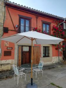 a table and chairs under an umbrella in front of a house at La Plazuela - Los Sitios de Aravalle 