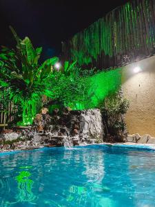 una piscina por la noche con luz verde en Pousada Casinha Velha, en Macacos