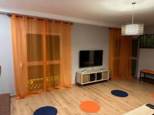a living room with a flat screen tv and orange curtains at Apartamentos adrian in Jerez de la Frontera