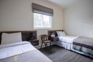 una camera con due letti e una sedia e una finestra di Hotel Mont-Tremblant a Mont-Tremblant