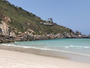 a beach with the ocean and houses on a hill at Suíte Trilha do Sol 2 in Arraial do Cabo