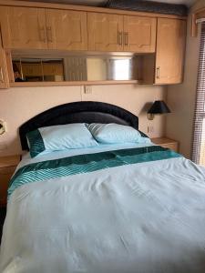 a large bed in a bedroom with wooden cabinets at Immaculate 2-Bed Static Caravan at Monrieth in Newton Stewart