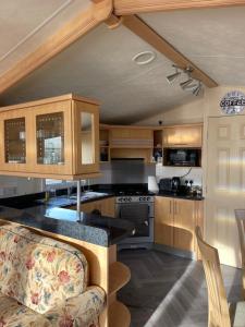 Immaculate 2-Bed Static Caravan at Monrieth في نيوتن ستيوارت: مطبخ بدولاب خشبي وقمة كونتر
