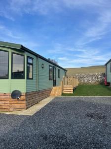 a green caravan with a deck and a building at Immaculate 2-Bed Static Caravan at Monrieth in Newton Stewart