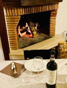 1 botella de vino y 2 copas en una mesa con chimenea en Casa Sunta, en Tarzo