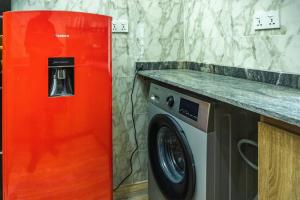 a red refrigerator next to a washing machine in a kitchen at Awesome 1-Bed-Apt With 24hrs Power & Fast WiFi in Lagos