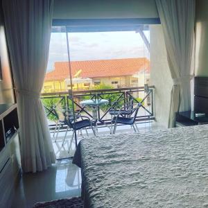 1 dormitorio con 1 cama y balcón con mesa y sillas en Flat Monte Castelo Gravata, en Gravatá
