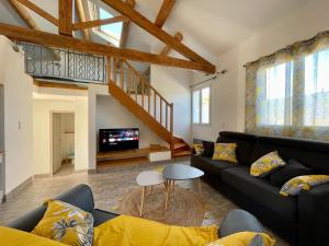 sala de estar con sofá y TV en La Remise de Guytou et Spa en Cheval-Blanc
