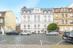 a large white building with cars parked in a parking lot at Apartments direkt am STAATSTHEATER,modern,zentral,ruhig,2 Zimmer,Netflix,Privatparkplatz auf dem Hof in Cottbus