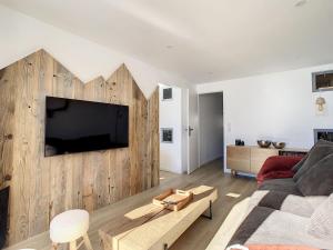 a living room with a couch and a tv on a wall at Apartment Les Burons-3 by Interhome in Les Menuires