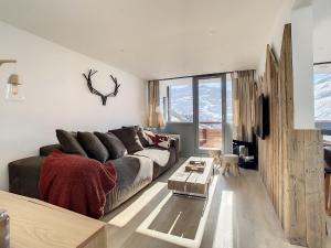 a living room with a couch and a table at Apartment Les Burons-3 by Interhome in Les Menuires