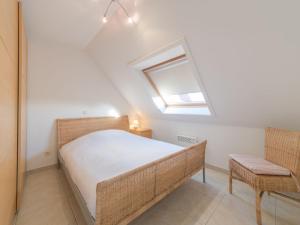 a bedroom with a bed and a window and a chair at Apartment Green Garden-6 by Interhome in De Haan