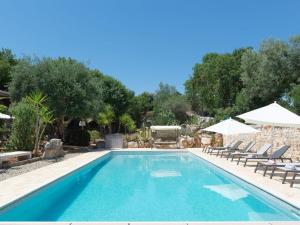 a swimming pool with lounge chairs and umbrellas at Trulli holiday home with private pool near Ostuni in Ostuni