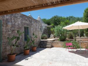 a patio with an umbrella and a table and chair at Trulli holiday home with private pool near Ostuni in Ostuni