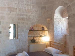 - une chambre dotée d'un mur en pierre et d'un lit dans l'établissement Trulli holiday home with private pool near Ostuni, à Ostuni