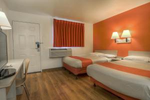 a hotel room with two beds and an orange wall at Motel 6-Chino, CA - Los Angeles Area in Chino