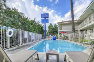 a swimming pool with a sign in front of a building at Motel 6-Chino, CA - Los Angeles Area in Chino