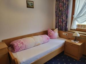 a small bedroom with a bed with pink pillows at Apartment LaFontana by Interhome in Kappl