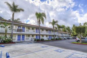 a building with blue doors and palm trees in a parking lot at Motel 6-Chino, CA - Los Angeles Area in Chino
