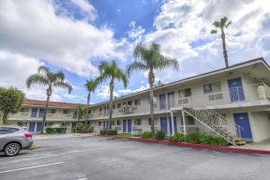 a parking lot in front of a building with palm trees at Motel 6-Chino, CA - Los Angeles Area in Chino