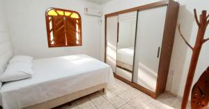 Schlafzimmer mit einem Bett, einem Fenster und einem Spiegel in der Unterkunft Casa Sapucaia - Praia in Santa Cruz Cabrália