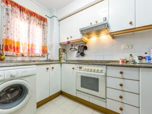 cocina con armarios blancos, lavadora y secadora en Apartment Solarium by Interhome, en Torredembarra
