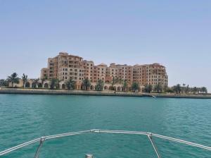 a boat in the water in front of a large building at الهُدىٰ غرفة إطلالة بحرية - عائلات One Room Sea View-ALHUDA in King Abdullah Economic City