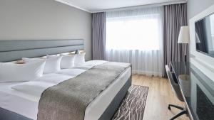 um quarto com uma cama grande e uma janela em Holiday Inn Berlin Airport - Conference Centre, an IHG Hotel em Schönefeld